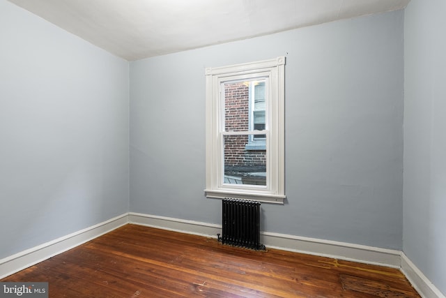 spare room featuring dark wood-type flooring and radiator heating unit