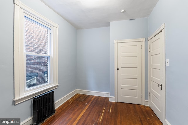 spare room with dark wood-type flooring and radiator