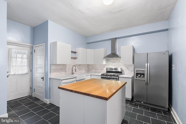 kitchen featuring wooden counters, white cabinetry, stainless steel appliances, a kitchen island, and wall chimney exhaust hood