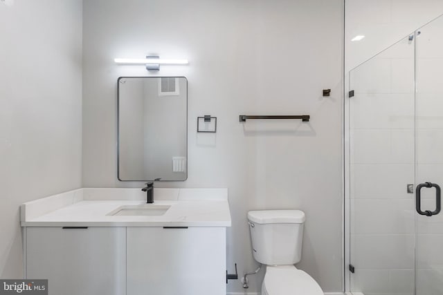 bathroom featuring a shower with door, vanity, and toilet