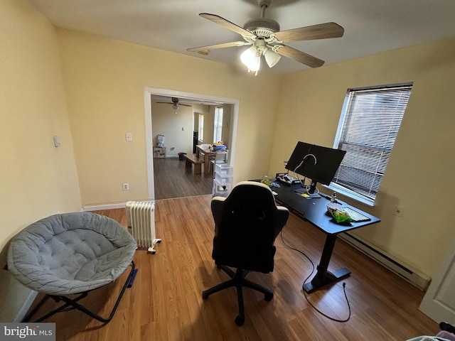 office space featuring hardwood / wood-style flooring, ceiling fan, radiator, and a baseboard heating unit