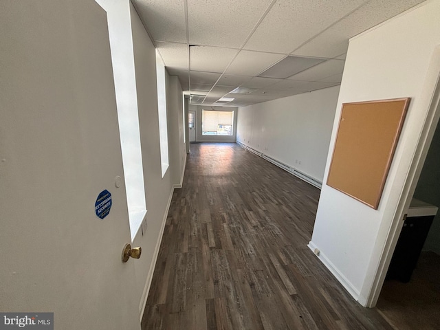 corridor with a drop ceiling and dark hardwood / wood-style flooring