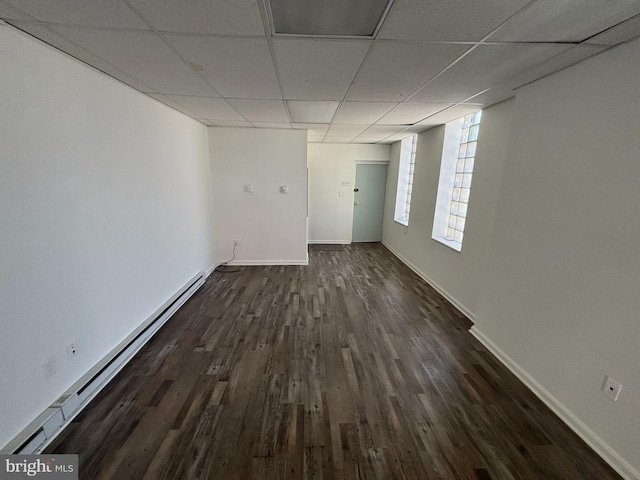 empty room with dark hardwood / wood-style flooring, a paneled ceiling, and baseboard heating