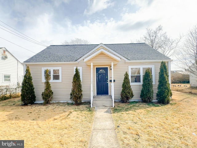 view of front of property with fence, a front lawn, and roof with shingles