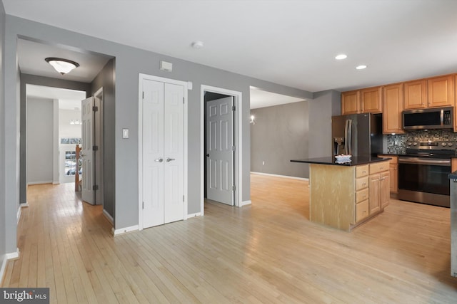 kitchen with stainless steel appliances, a center island, light hardwood / wood-style floors, and decorative backsplash