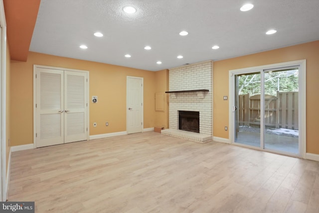 unfurnished living room featuring a fireplace, light hardwood / wood-style floors, and a textured ceiling