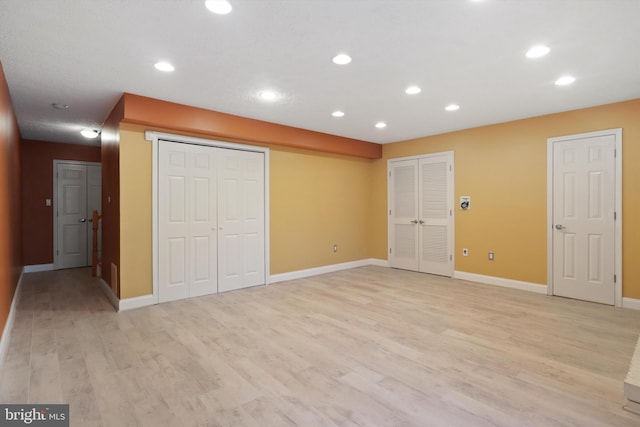 unfurnished bedroom featuring light hardwood / wood-style floors and two closets