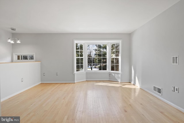 spare room featuring an inviting chandelier and light wood-type flooring