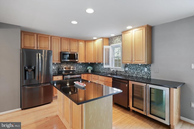 kitchen with a kitchen island, tasteful backsplash, sink, stainless steel appliances, and light wood-type flooring