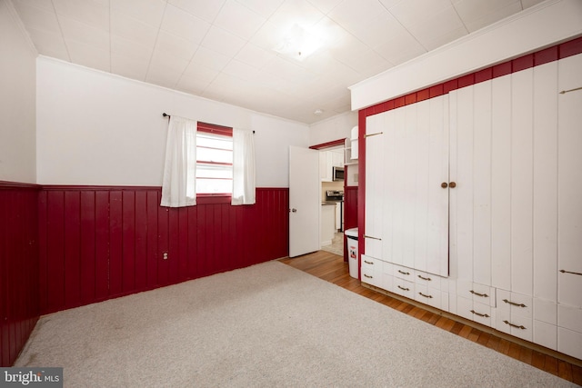 unfurnished bedroom featuring ornamental molding, wood-type flooring, and wooden walls