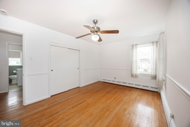 unfurnished bedroom with ceiling fan, light wood-type flooring, baseboard heating, and a closet