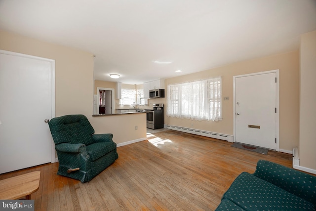 living area with light hardwood / wood-style floors and baseboard heating