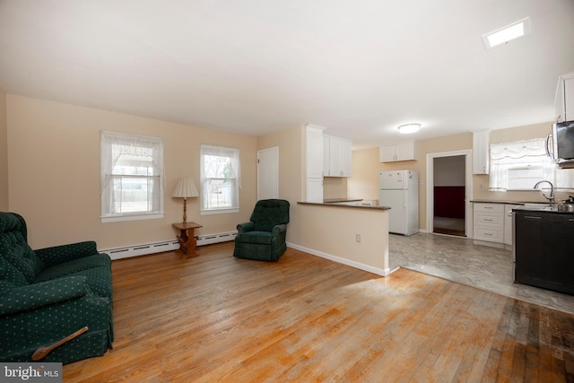 interior space with a baseboard radiator, sink, and light hardwood / wood-style floors