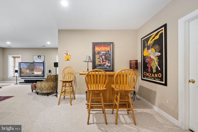 dining area with light carpet and bar area