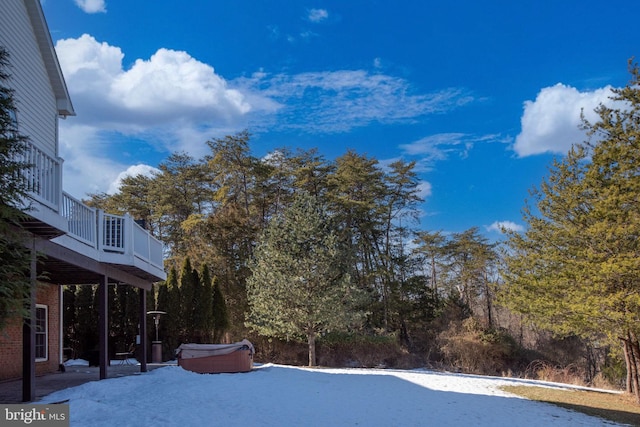 snow covered pool featuring a hot tub and a deck