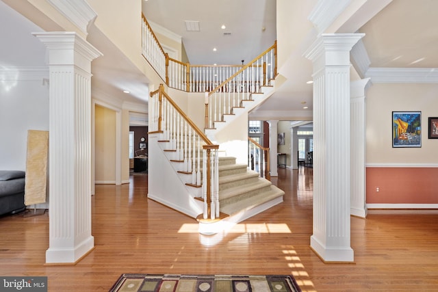 foyer entrance featuring decorative columns, ornamental molding, and light hardwood / wood-style flooring