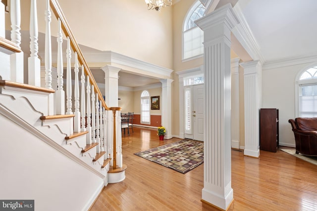 foyer with crown molding, hardwood / wood-style flooring, a wealth of natural light, and decorative columns