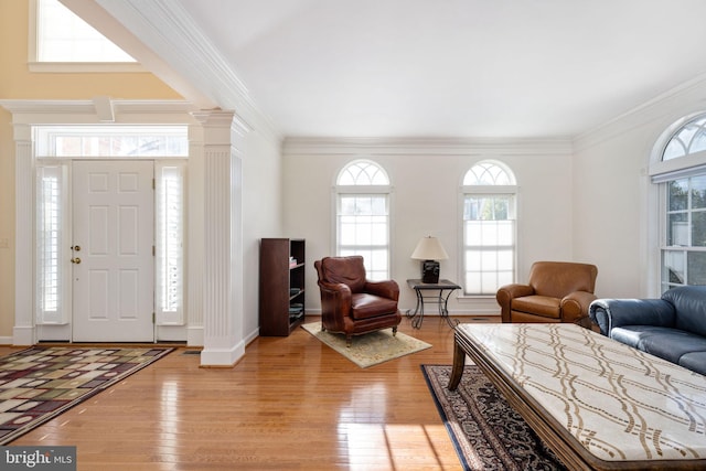 foyer entrance with ornate columns, ornamental molding, and light hardwood / wood-style floors