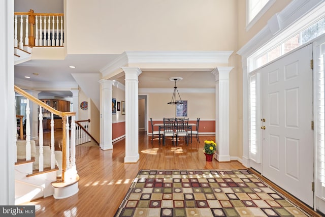 entryway featuring ornate columns, wood-type flooring, and a high ceiling