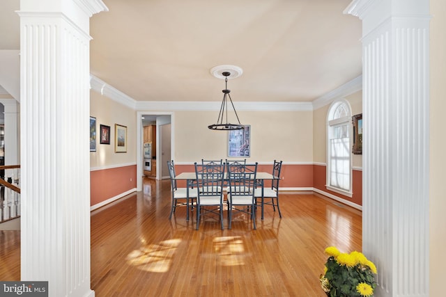 dining space with decorative columns, ornamental molding, and hardwood / wood-style floors