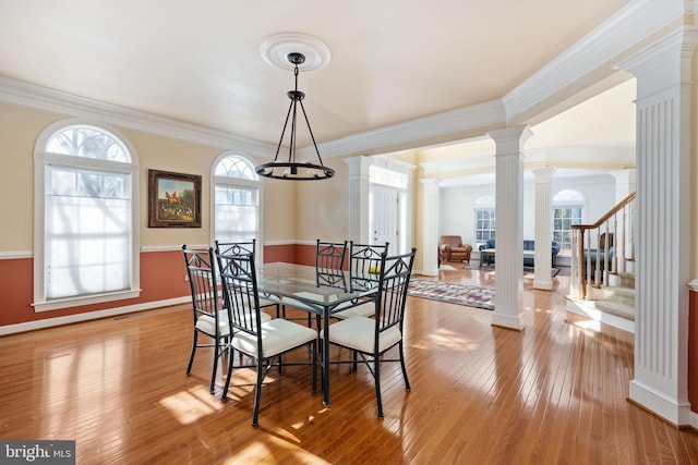 dining room with crown molding, light hardwood / wood-style floors, and decorative columns