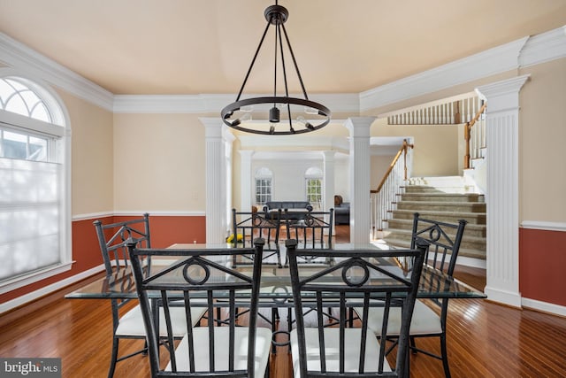 dining room with ornamental molding, decorative columns, and hardwood / wood-style floors