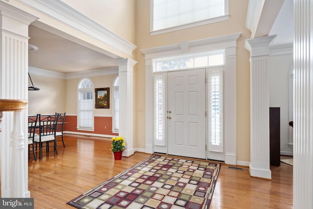 entrance foyer with crown molding, decorative columns, a high ceiling, and hardwood / wood-style flooring