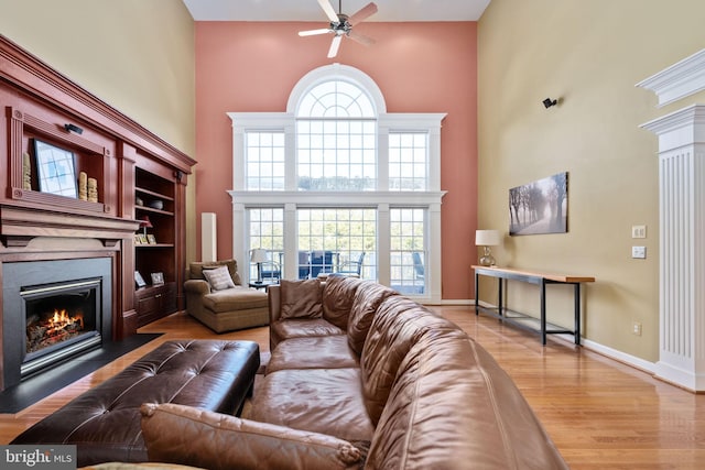 living room with ceiling fan, wood-type flooring, and a high ceiling