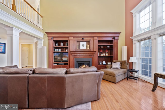 living room with decorative columns, a high ceiling, and light hardwood / wood-style floors