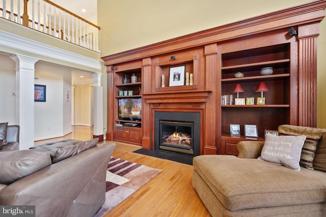 living room featuring decorative columns, built in features, and light wood-type flooring