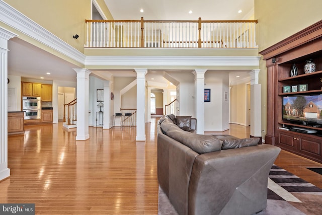 living room with light hardwood / wood-style flooring, decorative columns, and a high ceiling