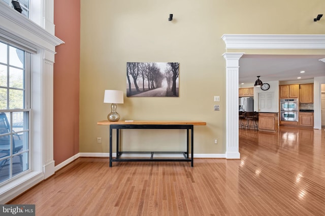 interior space featuring stainless steel appliances, hardwood / wood-style floors, and ornate columns