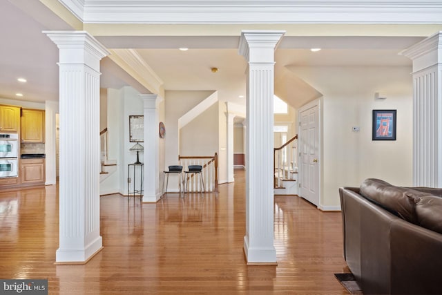 living room with crown molding, light wood-type flooring, and ornate columns