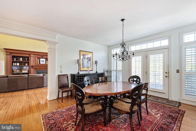 dining space featuring ornate columns, hardwood / wood-style floors, and an inviting chandelier