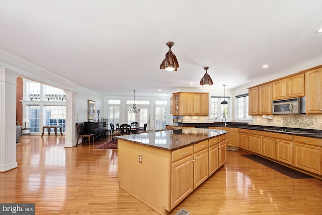 kitchen with dark stone countertops, hanging light fixtures, a kitchen island, and appliances with stainless steel finishes