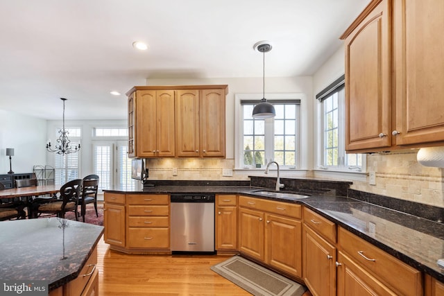 kitchen with pendant lighting, sink, dark stone countertops, and dishwasher