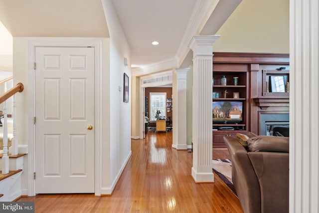 hall with ornate columns, crown molding, built in features, and light hardwood / wood-style floors