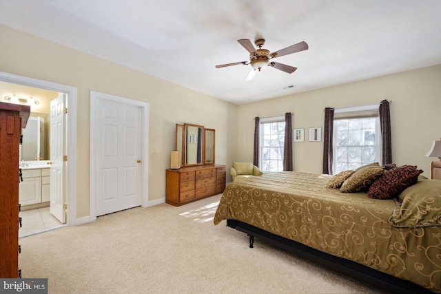 bedroom featuring light colored carpet, ceiling fan, and ensuite bathroom