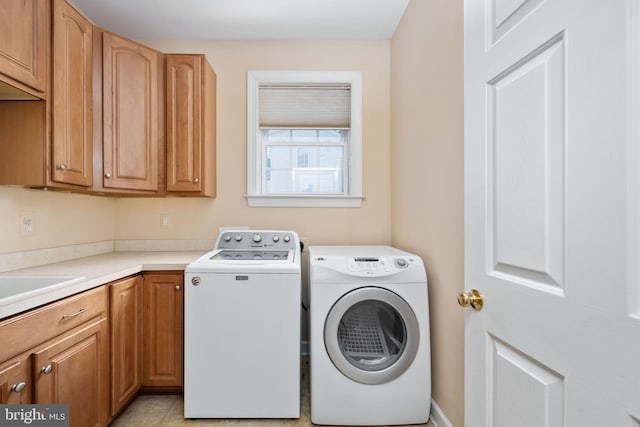 clothes washing area with cabinets, sink, and washer and dryer