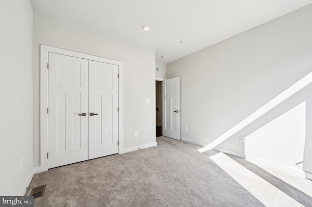 unfurnished bedroom with a closet and light carpet