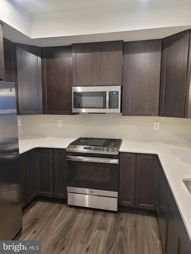 kitchen featuring stainless steel appliances, dark wood-type flooring, tasteful backsplash, and dark brown cabinetry