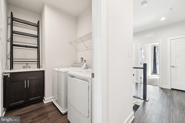 laundry area with dark hardwood / wood-style floors, washer and clothes dryer, and sink