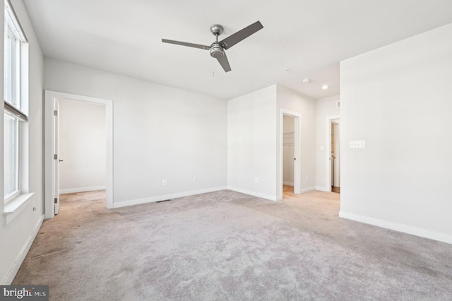 unfurnished bedroom featuring ceiling fan, light colored carpet, a walk in closet, and a closet