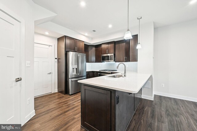 kitchen featuring kitchen peninsula, stainless steel appliances, dark brown cabinetry, pendant lighting, and sink