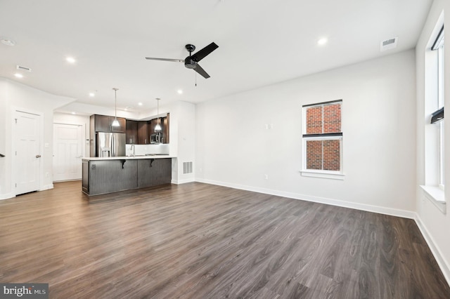 unfurnished living room with ceiling fan, sink, and dark wood-type flooring