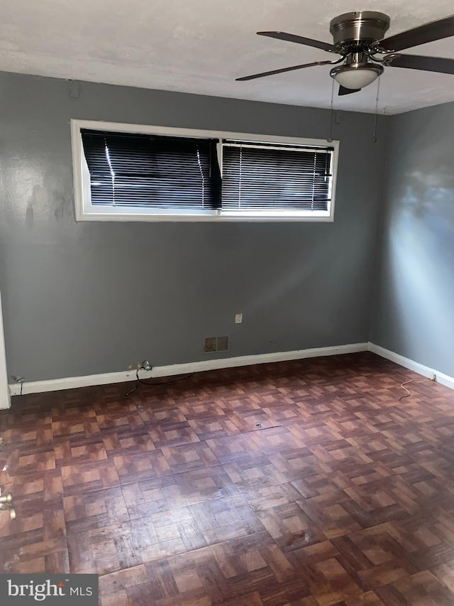 empty room featuring dark parquet floors and ceiling fan