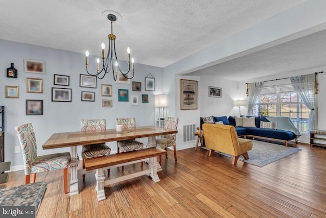 dining space featuring an inviting chandelier, a textured ceiling, and light hardwood / wood-style floors