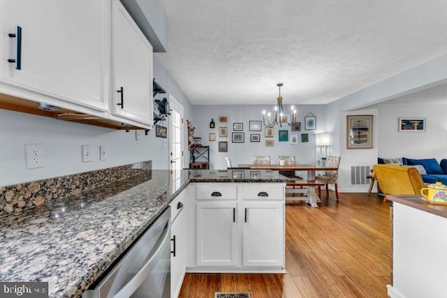 kitchen with light hardwood / wood-style flooring, dark stone countertops, kitchen peninsula, dishwasher, and white cabinets