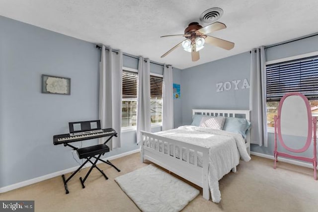 carpeted bedroom with ceiling fan and a textured ceiling