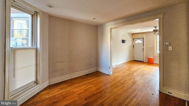 empty room with ceiling fan, a healthy amount of sunlight, and light wood-type flooring